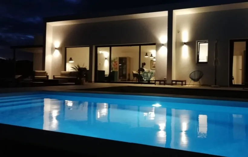 Pool lit with LED lights at night, in front of a house